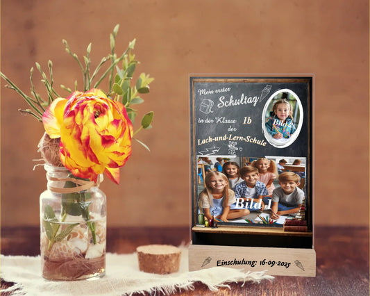 personalisierte-erinnerungstafel-15x20cm-aus-acrylglas-mit-2-fotos-name-der-schule-und-der-klasse-hintergrund-schultafel-bedruckt-mit-echtholz-standfuß-graviert-mit-einschulungsdatum-erinnerungstafel-steht-auf-rustikalem-tisch-neben-einer-rose