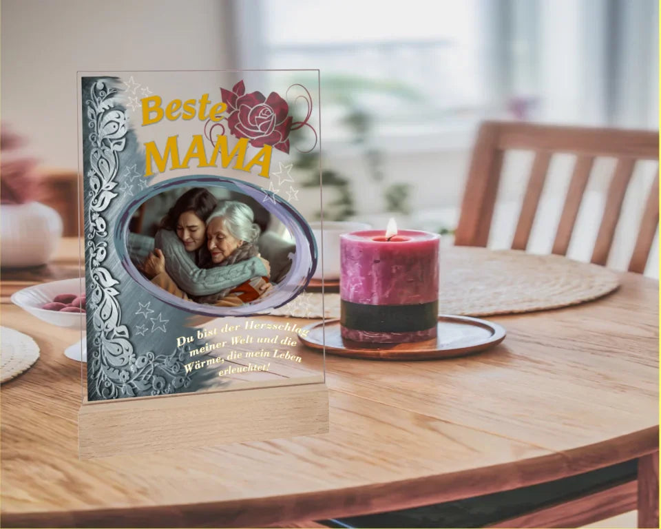 fotoaufsteller-15x20cm-aus-acryl-mit-echtholzsockel-mit-personalisierbaren-foto-silbernen-akzent-auf-der-linken-seite-und-einem-goldgelben-lebensbaum-über-dem-foto-steht-beste-mama-unter-dem-foto-steht-einer-der-fünf-wählbaren-sprüche-der-aufsteller-steht-auf-einem-esstisch-neben-kerze
