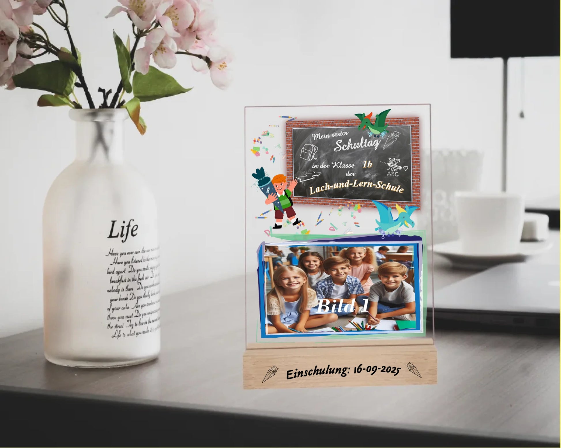 personalisierter-fotoaufsteller-15x20cm-mit-foto-name-der-schule-und-der-klasse-mit-graviertem-standfuß-mit-einschulungsdatum-fotoaufteller-steht-auf-einem-schreibtisch-neben-vase-mit-blumen