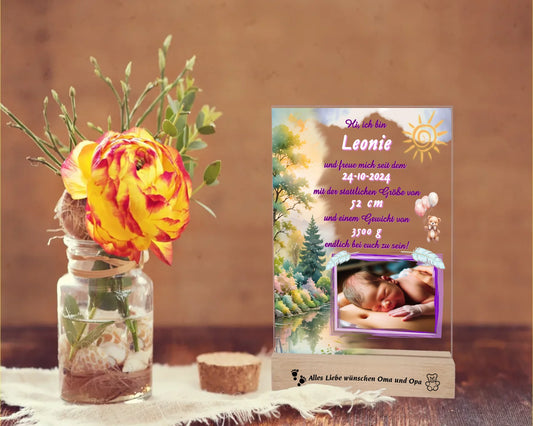 acrylglas-fotoaufsteller-15x20cm-mit-graviertem-standfuß-aus-holz-personalisierter-steckbrief-mit-geburtsdaten-und-foto-hauptfarbe-des-designs-pink-und-pasteltoene-standfuss-mit-wunschtext-graviert-fotoauftseller-steht-auf-rustikalem-holztisch-neben-einer-rose