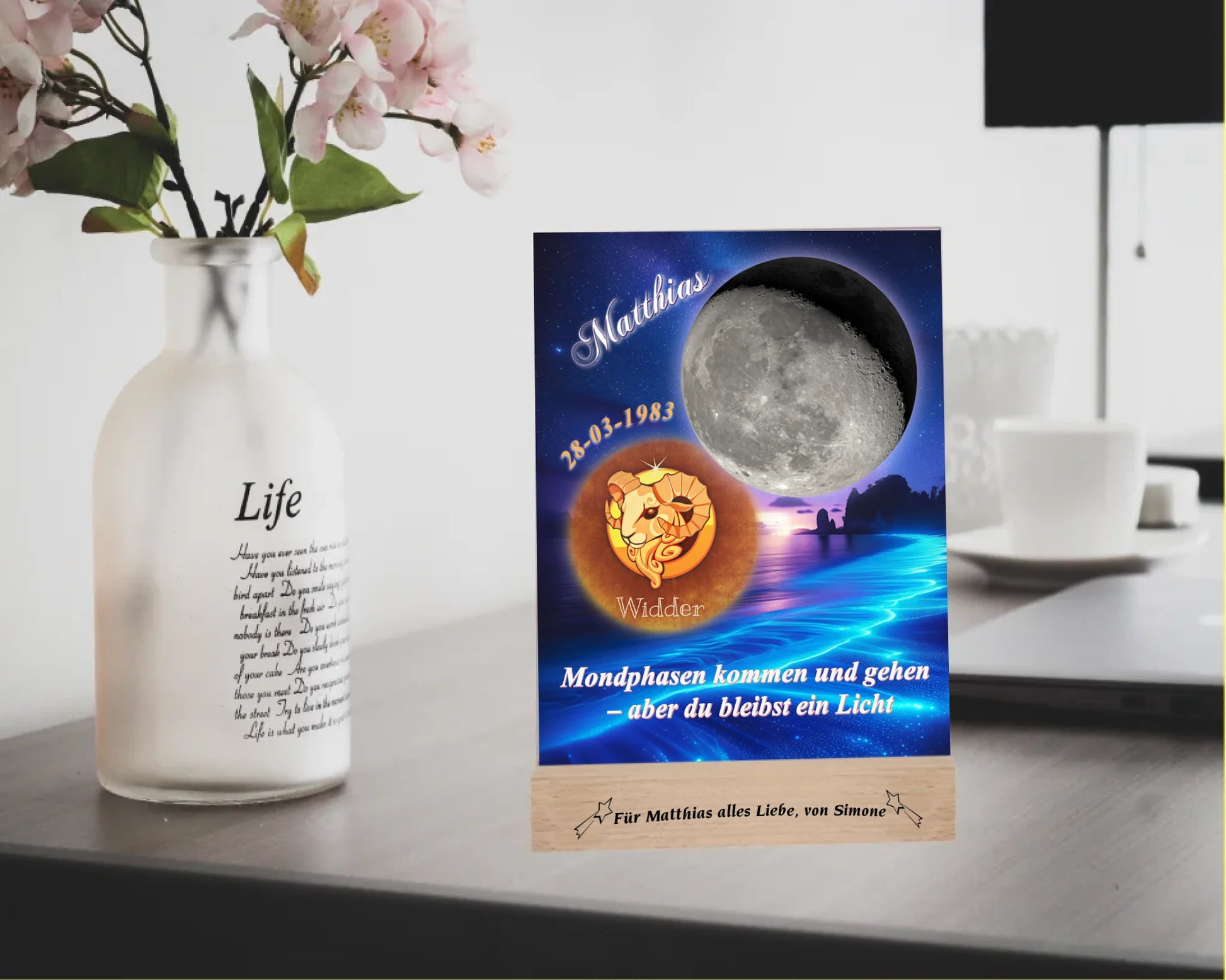 acrylglas-15x20cm-mit-graviertem-holzsockel-design-mit-personalisierter-mondphase-nach-datum-mit-sternzeichen-und-name-kurzer-spruch-monphasen-kommen-und-gehen-aber-du-bleibst-ein-licht-designhintergrund-brandung-meer-in-neon-blau-sternzeichen-ist-bronzefarben-dargestellt-und-der-mond-silber-acrylglas-steht-auf-einem-schreibtisch-neben-einer-vase-mit-blumen