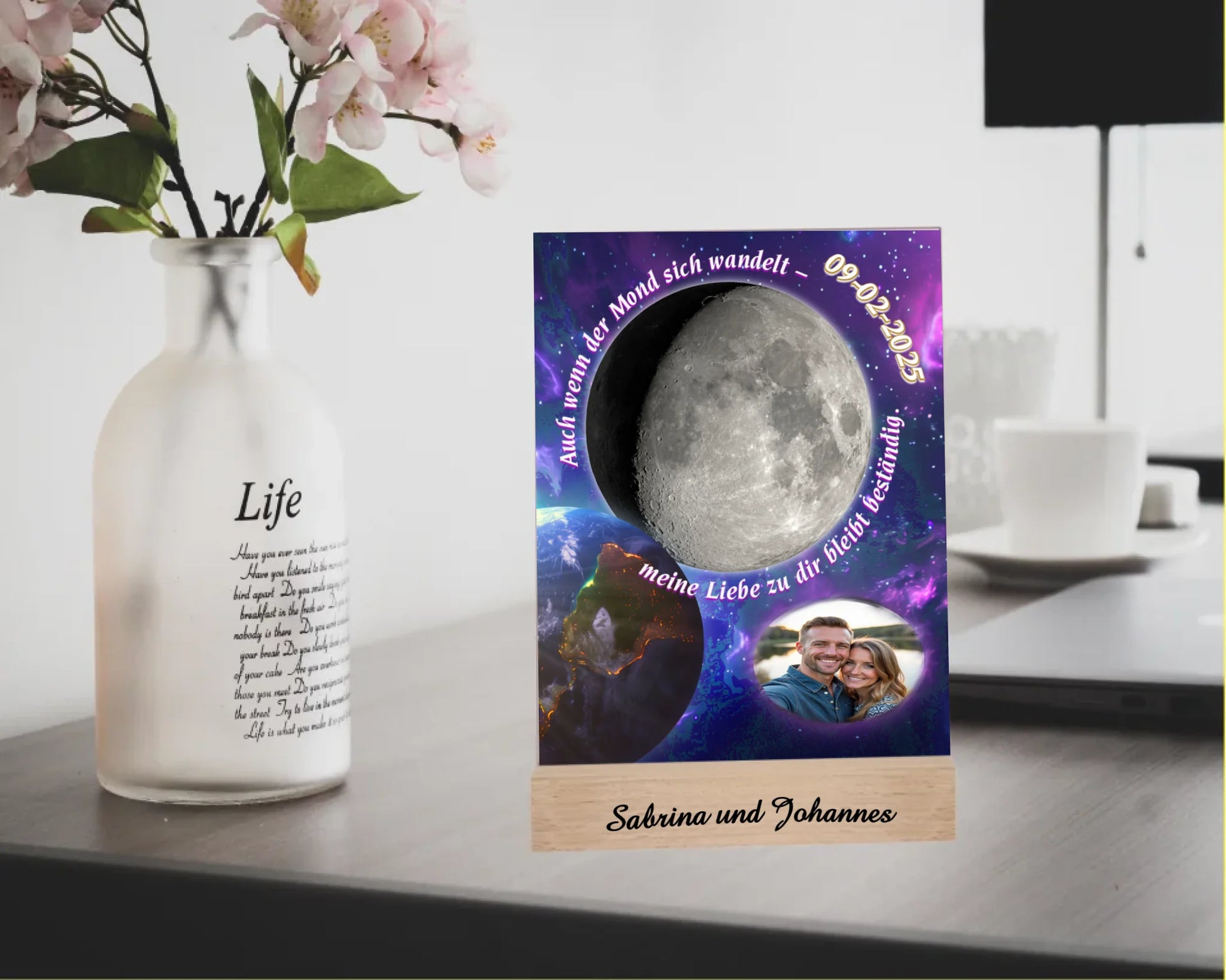 acrylaufsteller-15x20cm-mit-graviertem-holzsockel-acrylglas-ist-personalisiert-mit-foto-datum-und-bild-der-dazu-passenden-mondphase-im-vordergrund-ist-die-erde-zu-sehen-und-als-hintergrund-dient-ein-weltall-motiv-mit-einem-farbverlauf-von-dunkelblau-bis-violett-um-den-mond-befindet-sich-ein-schriftzug-mit-dem-text-auch-wenn-der-mond-sich-wandelt-meine-liebe-zu-dir-bleibt-beständig-acryllas-steht-mit-einem-gravierten-holzsockel-personalisiert-mit-namen-oder-wunschtext-acrylaufsteller-auf-schreibtisch
