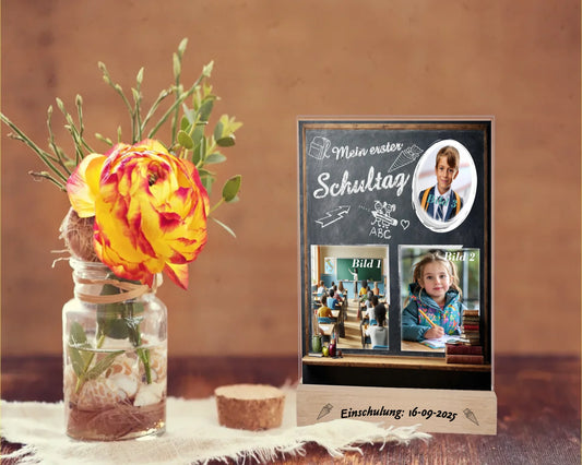 personalisierter-fotoaufsteller-acryl-15x20cm-optik-schultafel-mit-drei-fotos-gravur-am-holzsockel-mit-einschulungsdatum-steht-auf-rustikalem-holztisch-neben-einer-rose