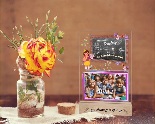 personalisierter-fotoaufsteller-15x20cm-mit-foto-name-der-schule-und-der-klasse-mit-graviertem-standfuß-mit-einschulungsdatum-fotoaufteller-steht-auf-rusikalem-tisch-neben-einer-rose