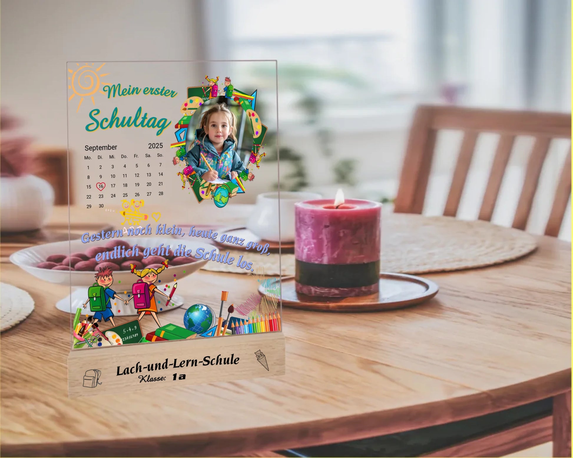 personalisierter-fotoaufsteller-aus-acryl-15x20cm-mit-foto-und-kalenderblatt-zum auswählen-des-datums-zwischen-bunten-schulmotiven-auf-graviertem-holzsockel-mit-name-der-schule-und-der-klasse-fotoaufsteller-steht-auf-esstisch