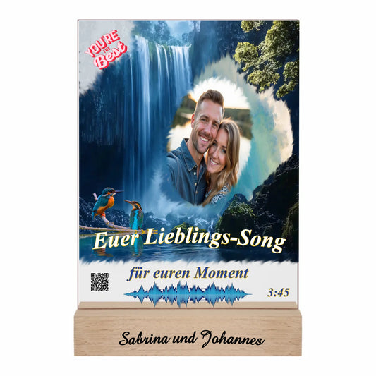 acrylaufsteller-15x20cm-personalisiert-mit-foto-titel-und-interpret-des-ausgewählten-songs-mit-qr-code-und-gravierten-namen-am-holzsockel-design-hintergrund-ein-wasserfall-in-strahlendem-blau-aufsteller-vor-weissem-hintergrund