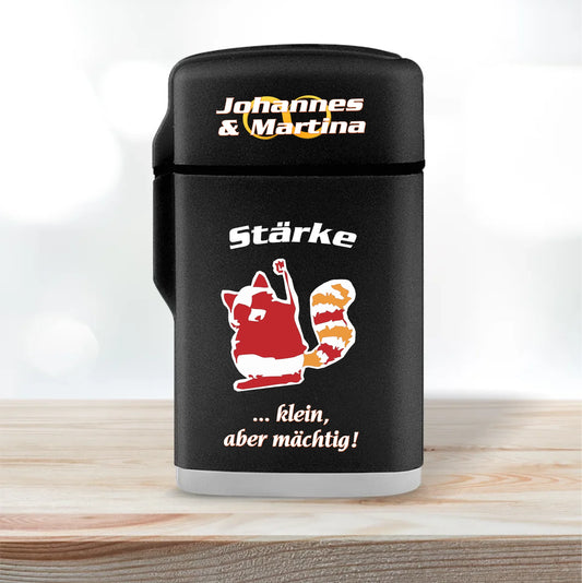 jetflame-feuerzeug-schwarz-mit-deckel-geschlossen-nikolausgeschenk-kollegen-personalisierbar-mit-namen-und-charaktereigenschaft-dazu-erscheint-ein-passendes-motiv-hier-waschbär-in-rot-orange-und-weißer-text-staerke-klein-aber-maechtig