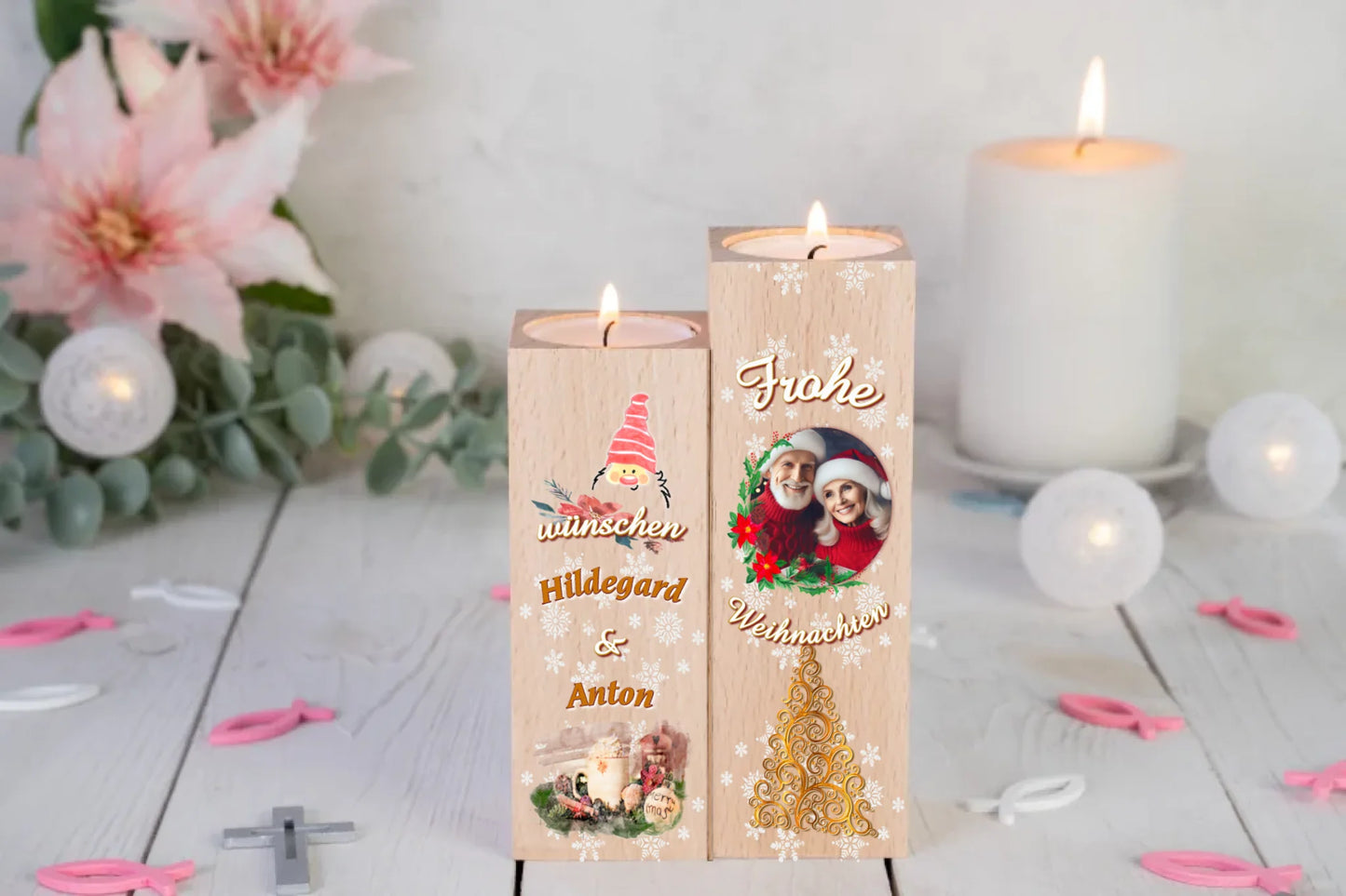 teelichthalter-massiv-holz-2er-set-4,5x4,5cm-12-und-14cm-hoch-personalisiert-mit-foto-und-zwei-namen-weihnachtliches-design-kerzenhalter-rechts-mit-schriftzug-frohe-ueber-dem-foto-mit-ovalem-rahmen-aus-zweigen-darunter-schriftzug-weihnachten-ganz-unten-weihnachtsbaum-ornament-in-gold-design-kerzenhalter-links-wichtelkopf-mit-roter-muetze-darunter-schriftzug-wuenschen-und-die-beiden-personalisierten-namen-ganz-unte-weihnachtliches-gedeck-in-aquarell-optik-teelichhalter-stehen-vor-lilien-und-weisser-kerze