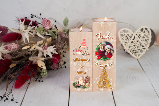 teelichthalter-massiv-holz-2er-set-4,5x4,5cm-12-und-14cm-hoch-personalisiert-mit-foto-und-zwei-namen-weihnachtliches-design-kerzenhalter-rechts-mit-schriftzug-frohe-ueber-dem-foto-mit-ovalem-rahmen-aus-zweigen-darunter-schriftzug-weihnachten-ganz-unten-weihnachtsbaum-ornament-in-gold-design-kerzenhalter-links-wichtelkopf-mit-roter-muetze-darunter-schriftzug-wuenschen-und-die-beiden-personalisierten-namen-ganz-unte-weihnachtliches-gedeck-in-aquarell-optik-teelichhalter-stehen-vor-roten-trockenblumen