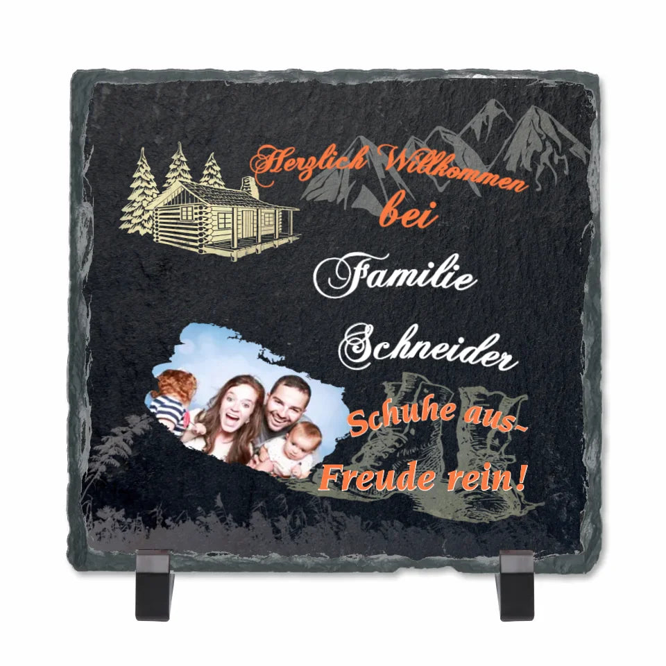 schieferplatte-quadratisch-15x15-cm-mit-standfuß-bedruckt-mit-persönlichem-foto-und-familienname-design-mit-motiven-wie-berge-wanderschuhe-blockhütte-beschriftung lautet-herzlich-willkommen-bei-familie-schneider-schuhe-aus-freude-rein