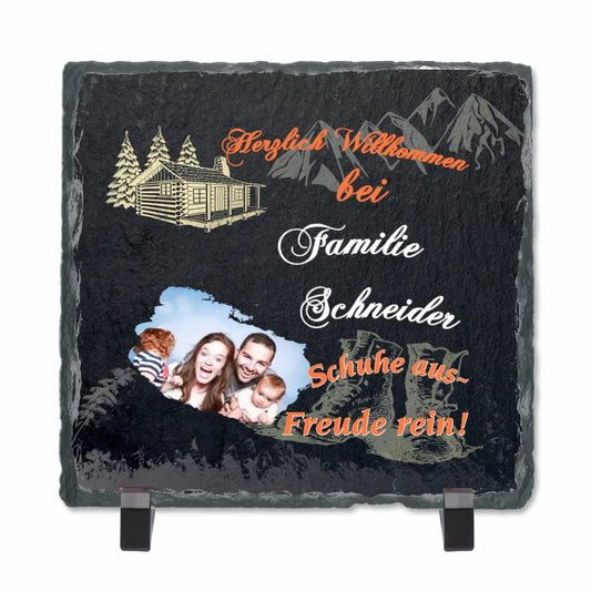 schieferplatte-quadratisch-15x15-cm-mit-standfuß-bedruckt-mit-persönlichem-foto-und-familienname-design-mit-motiven-wie-berge-wanderschuhe-blockhütte-beschriftung lautet-herzlich-willkommen-bei-familie-schneider-schuhe-aus-freude-rein