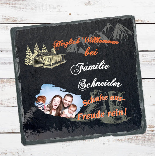 schieferplatte-quadratisch-15x15-cm-bedruckt-mit-persönlichem-foto-und-familienname-design-mit-motiven-wie-berge-wanderschuhe-blockhütte-beschriftung lautet-herzlich-willkommen-bei-familie-schneider-schuhe-aus-freude-rein