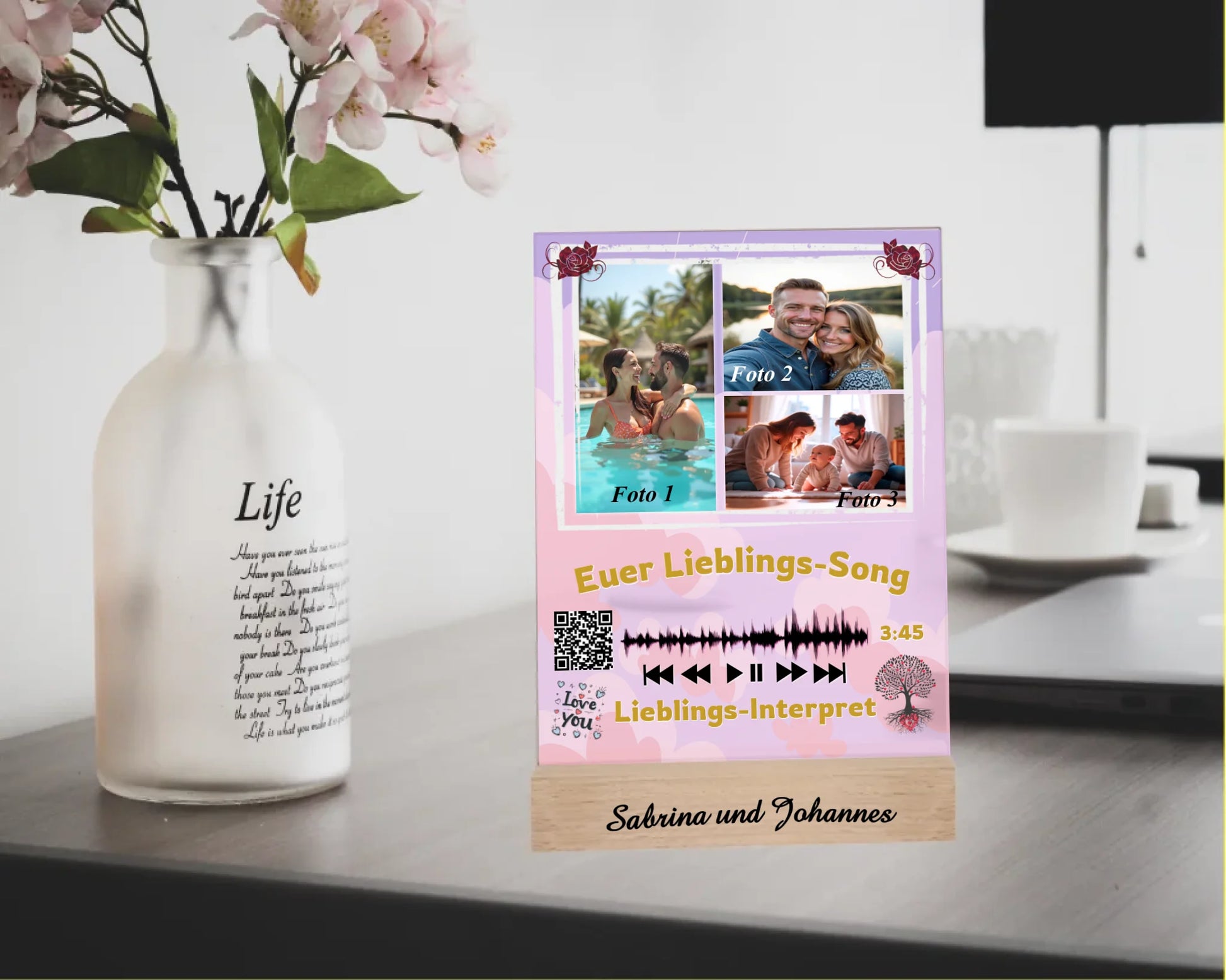 acrylglas-15x20cm-mit-graviertem-standfuss-aus-echtholz-acrylglas-mit-3-fotos-und-ausgewähltem-songtitel-und-interpret-mit-qr-code-design-hintergrund-pastell-rosa-in-verschiedenen-farbtoenen-standfss-graviert-mit-namen-oder-wunschtext-acrylaufsteller-steht-auf-schreibtisch-neben-einer-vase-mit-blumen