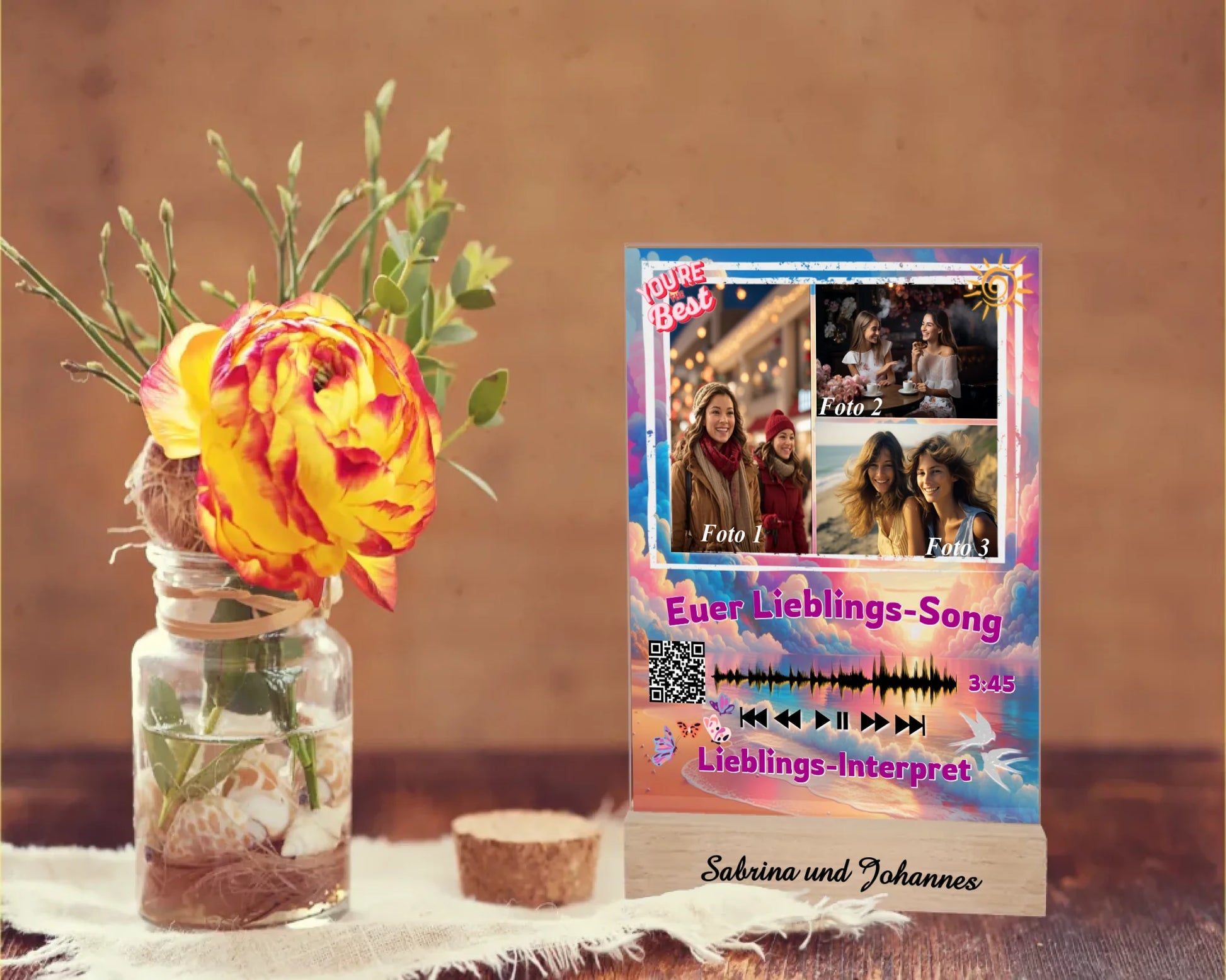acrylglas-15x20cm-mit-graviertem-standfuss-aus-echtholz-acrylglas-mit-3-fotos-und-ausgewähltem-songtitel-und-interpret-mit-qr-code-design-hintergrund-pastell-rosa-und blau-in-verschiedenen-farbtoenen-standfss-graviert-mit-namen-oder-wunschtext-acrylaufsteller-steht-auf-rustikalem-holztisch-neben-einer-rose