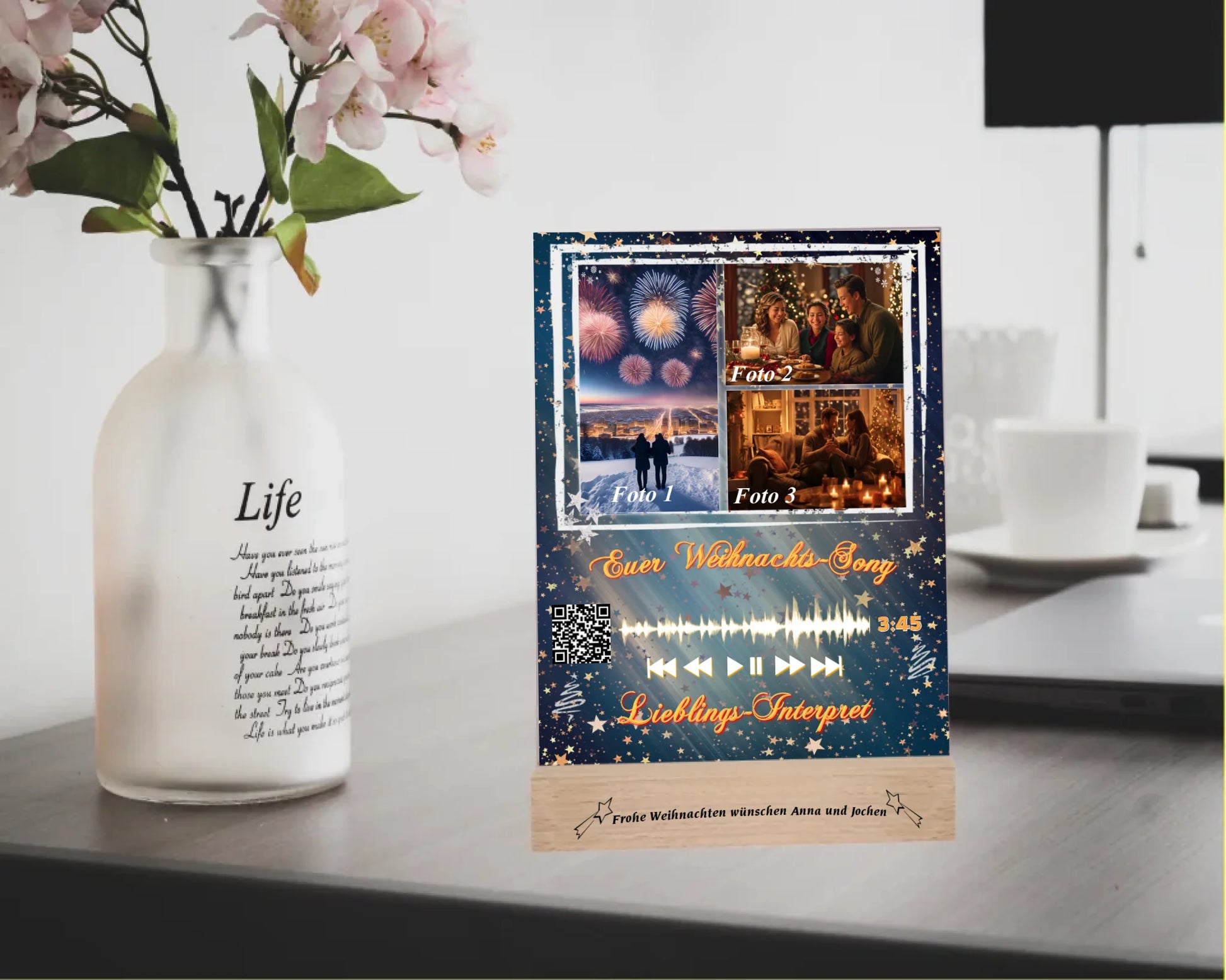 acrylglas-15x20cm-mit-graviertem-standfuss-aus-echtholz-nikolausgeschenk-mit-3-fotos-und-ausgewähltem-songtitel-und-interpret-mit-qr-code-design-hintergrund-dunkelgrün-mit verlauf-in-die farbe-silber-mit-vielen-kleinen-sternen-standfuss-graviert-mit-namen-oder-wunschtext-acrylaufsteller-steht-auf-schreibtisch-neben-vase-mit-blumen