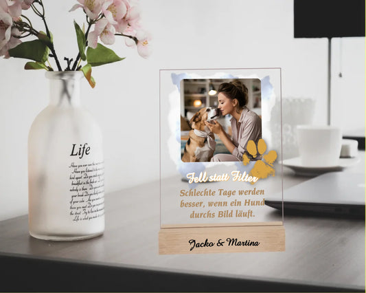 acrylglas-15x20cm-mit-echtholz-standfuss-personalisiert-mit-eigenem-foto-auf-wolken-als-hintergrund-pfotenabdruck-am-rand-des-fotos-darunter-einer-der-sechs-sprueche-zur-hund-mensch-beziehung-oder-eigener-text-holzsockel-optional-mit-namen-graviert-fotoaufsteller-steht-auf-schreibtisch