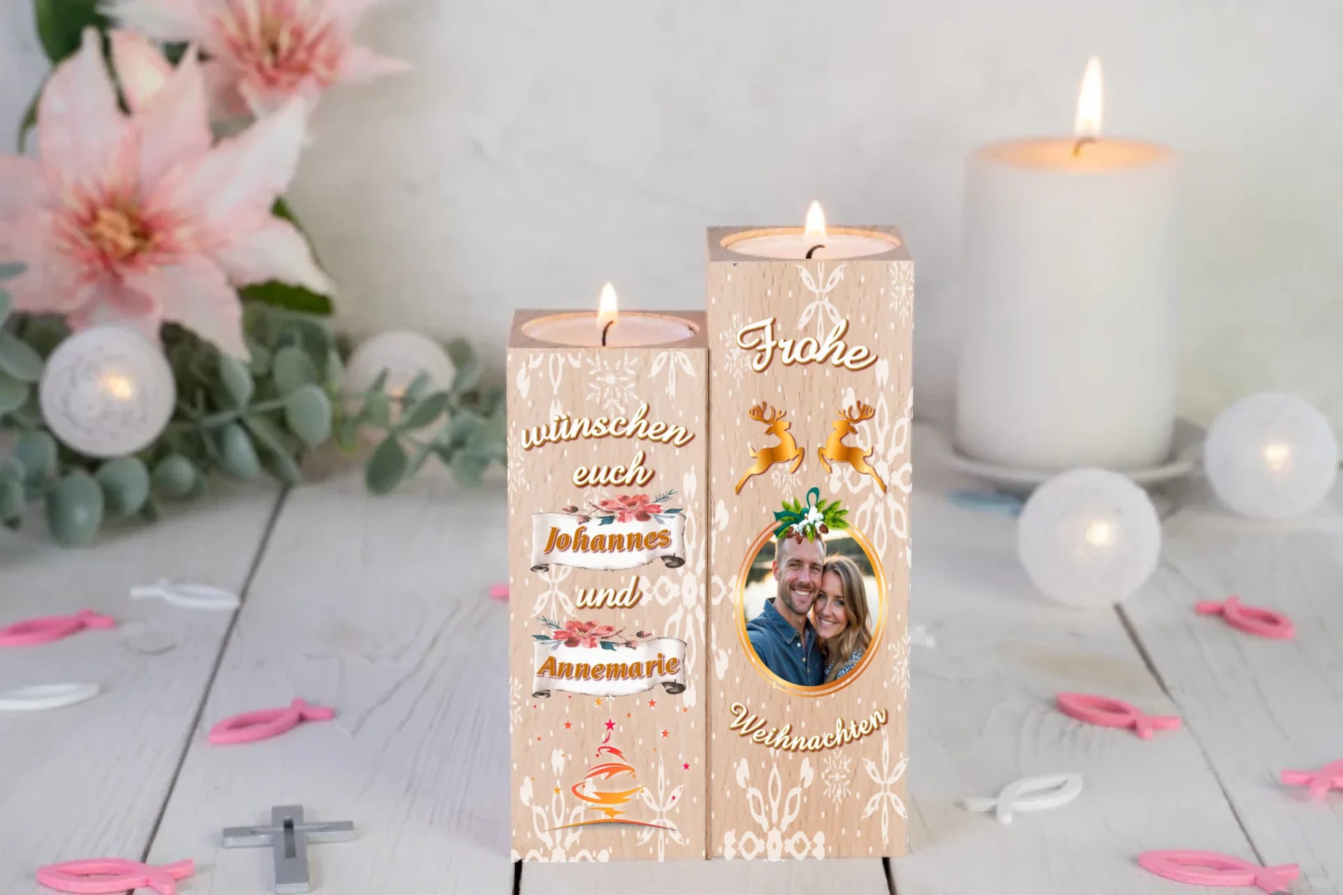 teelichthalter-massiv-holz-2er-set-4,5x4,5cm-12-und-14cm-hoch-personalisiert-mit-foto-und-zwei-namen-weihnachtliches-design-kerzenhalter-rechts-mit-schneeflocken-2-rentier-umrissen-in-gold-ueber-dem-foto-mit-ovalem-goldenem-rahmen-ganz-oben-steht-frohe-und-ganz-unten-steht-weihnachten-design-kerzenhalter-links-schriftzug-wuenschen-euch-dann-die-persnalisierten-namen-auf-schriftrolle-teelichthalter-steht-auf-weißem-tisch-im-hintergrund-liegen-lilien