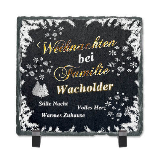 schieferplatte-schwarz-quadratisch-mit-standfuß-beschriftung-in-gold-und-weiß-text-lautet-weihnachten-bei-familie-personalisierter-name-design-mit-weihnachtlichen-motiven-wie-verschneite-zweige-und-schneeflocken