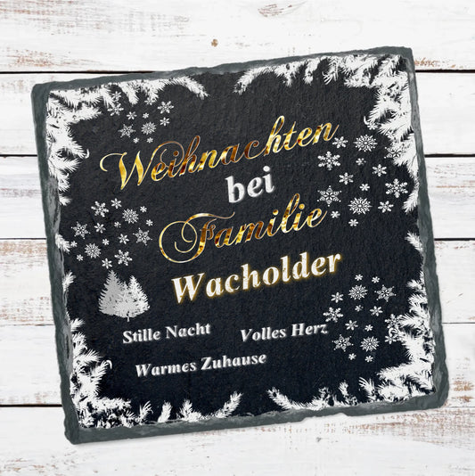 schieferplatte-schwarz-quadratisch-beschriftung-in-gold-und-weiß-text-lautet-weihnachten-bei-familie-personalisierter-name-design-mit-weihnachtlichen-motiven-wie-verschneite-zweige-und-schneeflocken