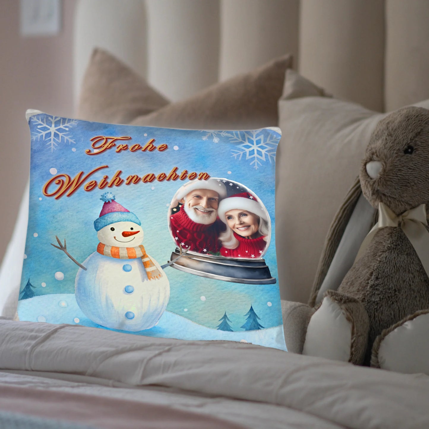 kissen-40x40-cm-mit-foto-vorderseite-mit-winterlandschaft-in-hellblau-und-schneemann-daneben-das-foto-in-einer-schneekugel-kissen-steht-in-einem-bett-neben-einem-kuscheltier
