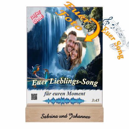 acrylaufsteller-15x20cm-personalisiert-mit-foto-titel-und-interpret-des-ausgewählten-songs-mit-qr-code-und-gravierten-namen-am-holzsockel-design-hintergrund-ein-wasserfall-in-strahlendem-blau-fotoaufsteller-mit-hinweis-zu-personalisierung