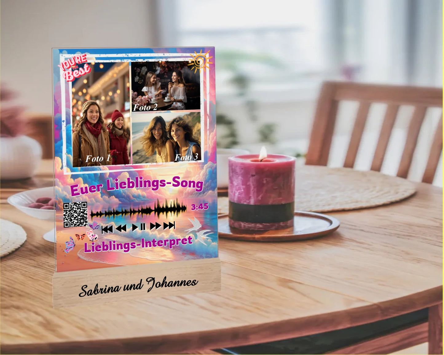 acrylglas-15x20cm-mit-graviertem-standfuss-aus-echtholz-acrylglas-mit-3-fotos-und-ausgewähltem-songtitel-und-interpret-mit-qr-code-design-hintergrund-pastell-rosa-und blau-in-verschiedenen-farbtoenen-standfss-graviert-mit-namen-oder-wunschtext-acrylaufsteller-steht-auf-esstisch-neben-einer-kerze