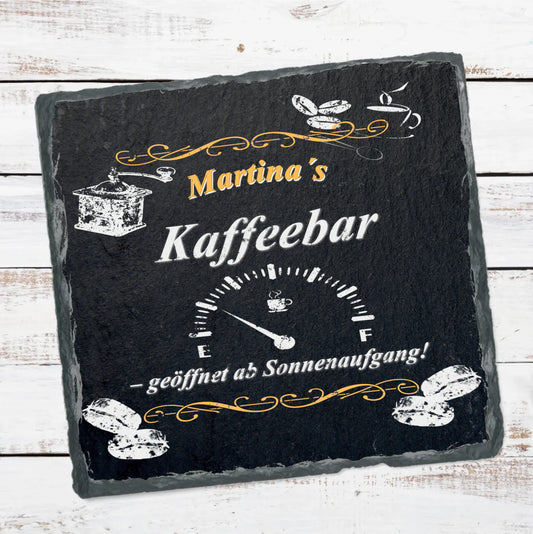 personalisierte-schieferplatte-quadratisch-schwarz-mit-name-und-spruch-geöffnet-ab-sonnenaufgang-und motiven-wie-kaffeebohnen-und-kaffeemühle-und-einer-fast-leeren-tankanzeige