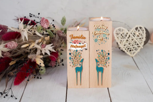teelichthalter-massiv-holz-2er-set-4,5x4,5cm-12-und-14cm-hoch-personalisiert-mit-familiennamen-weihnachtliches-design-rechter-kerzenhalter-oben-schriftzug-weiss-merry-christmas-auf-leicht-transparente-schneeflocken-und-weihnachtskugeln-darunter-umriss-rentier-in-dezentem-tuerkies-design-kerzenhalter-links-schriftzug-familie-darunter-personalisierter-familienname-auf-schriftrolle-und-ganz-unten-wieder-umriss-rentier-in-dezentem-tuerkies-teelichthalter-stehen-vor-roten-trockenblumen